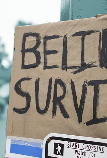 A photo of a sign that says "Believe Survivors"