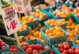 A photo of vegetables including cherry tomatoes and corn, at a farmer's market.