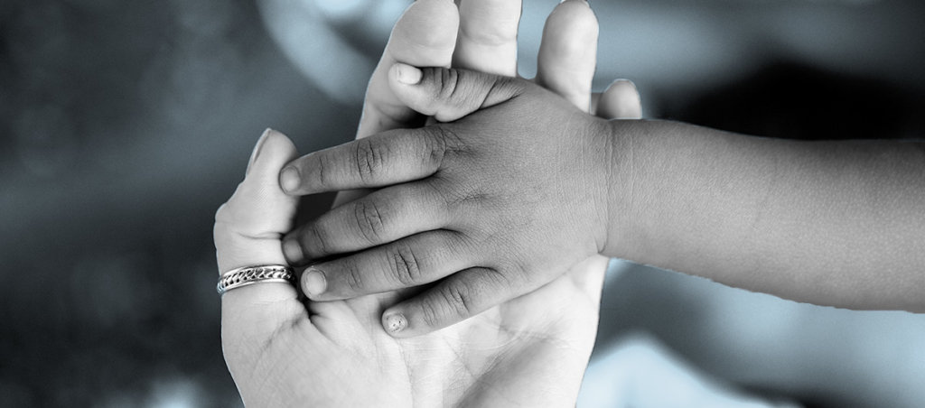 A photo of a Black kid's hand in a white woman's hand.