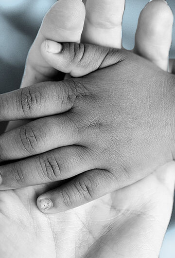 A photo of a Black kid's hand in a white woman's hand.
