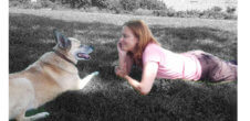 A photo of Kate Christensen looking at her dog.