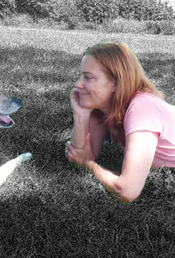 A photo of Kate Christensen looking at her dog.