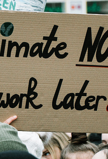 A photo from a climate change protest with the sign, "Climate Now, Homework later" that is visible.