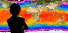A woman standing in front of a map of the world which is showing the visualization of different temperatures.