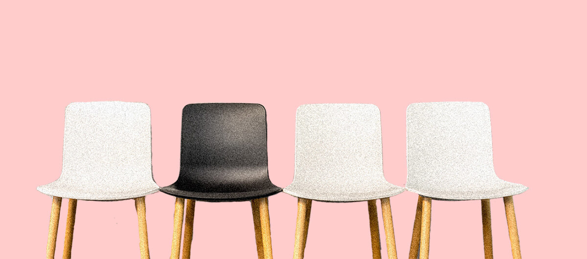 A photo of four chairs. Three are white and one is black.