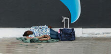 A photo of a Black person lying on a blanket outside.