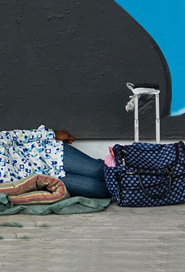 A photo of a Black person lying on a blanket outside.