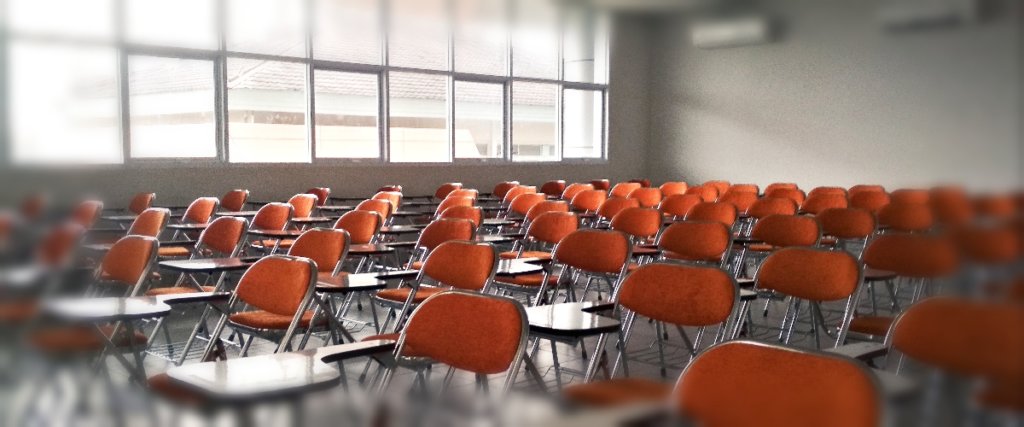 A photo of a classroom with chairs with desks being attached to them.