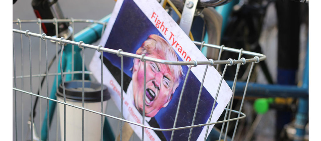A picture of a bike cart with a sign that says "Fight Tyranny" with an illustration of Donald Trump in it.
