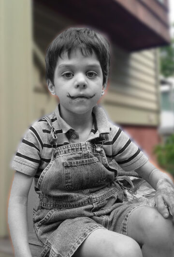 A photo of a young kid sitting outside.