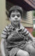 A photo of a young kid sitting outside.