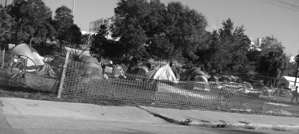 A black and white photo of tents that homeless people live in in a field