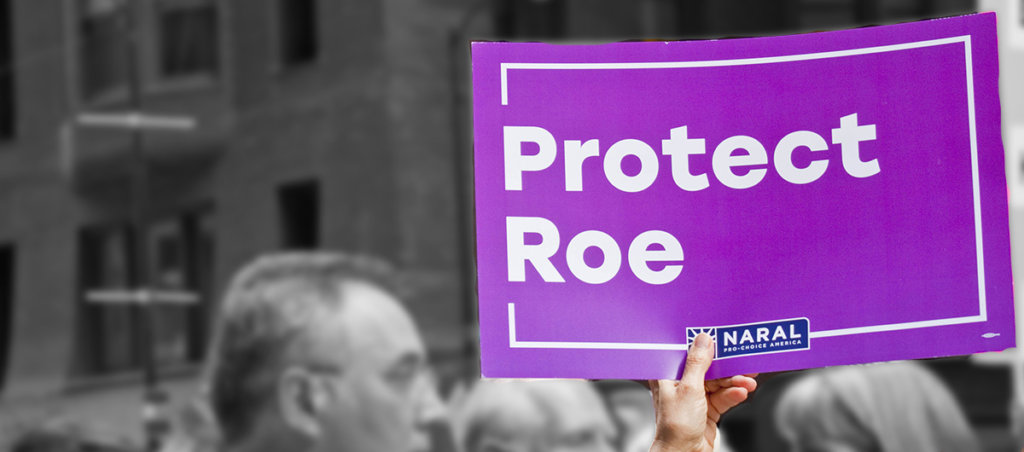 A photo from a protest with someone holding a sign that says "Protect Roe"