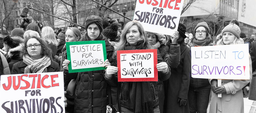 A photo of mainly women at a protest holding signs that say, "Justice for Survivors," "Justice for Survivors," and "Listen to Survivors"