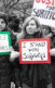 A photo of mainly women at a protest holding signs that say, "Justice for Survivors," "Justice for Survivors," and "Listen to Survivors"