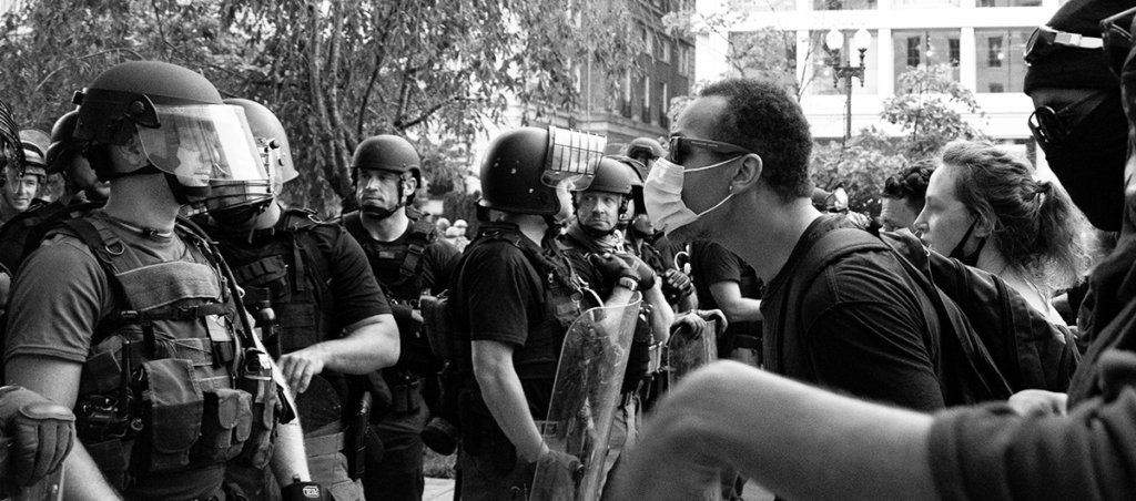 A Black and white photo of protestors and police in riot gear