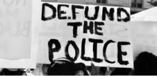 A photo from a protest of a sign that says "Defund the Police."