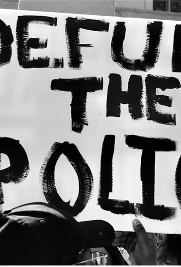 A photo from a protest of a sign that says "Defund the Police."