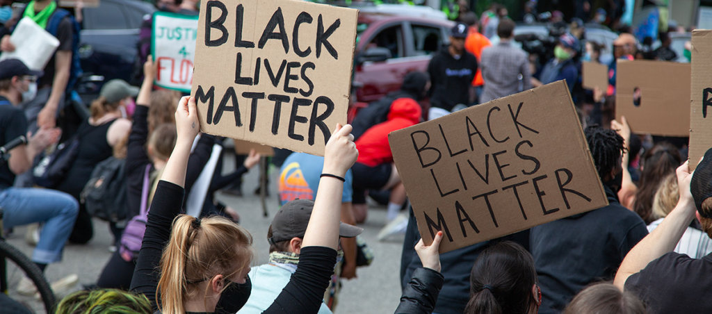 A photo of a Black Lives matter protest. Protestors are holding signs that says "Black Lives Matter."