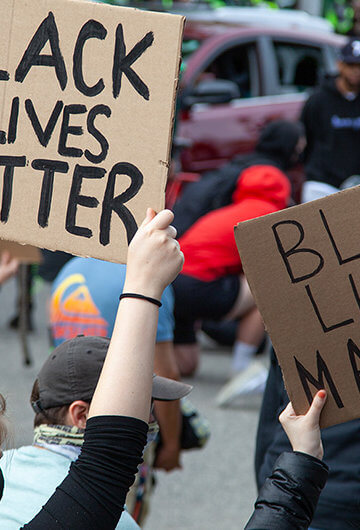 A photo of a Black Lives matter protest. Protestors are holding signs that says "Black Lives Matter."