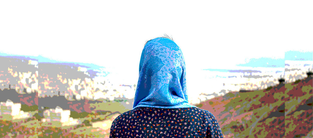 A woman in hijab looking out at mountains.