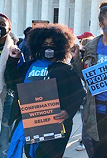 A group of people at a protest wearing "Action Now" shirts.