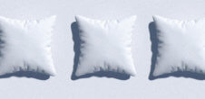 Three white pillows in a row on light blue background.