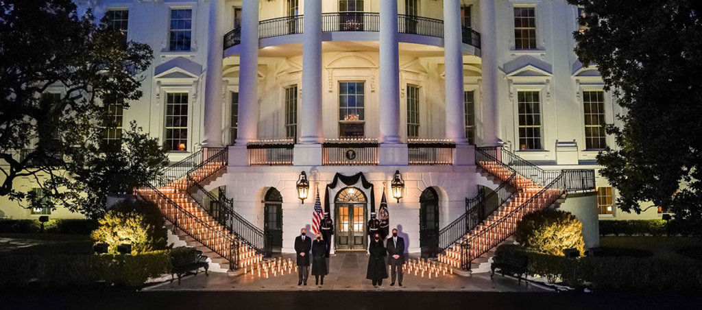 Image of White House rotunda with 500 candles representing 500,000 deaths. Vice President Kamala Harrs, Second Gentleman Doug Emhoff, President Joe Biden and First Lady Jill Biden stand solemnly in front of the display.
