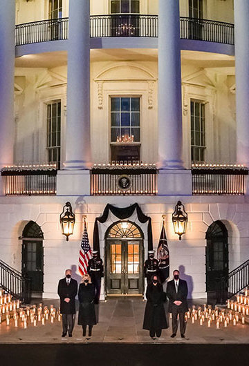 Image of White House rotunda with 500 candles representing 500,000 deaths. Vice President Kamala Harrs, Second Gentleman Doug Emhoff, President Joe Biden and First Lady Jill Biden stand solemnly in front of the display.