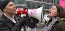 man with bullhorn that says pro-life on it screaming at woman at anti abortion protest