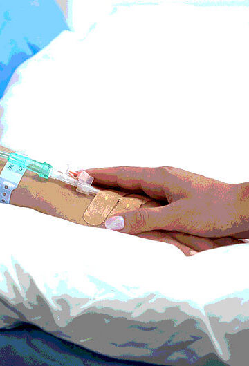 A doctor holding the hand of a woman who is lying in a hospital bed