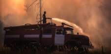 Person on a truck with a hose fighting back wildfire with water