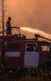 Person on a truck with a hose fighting back wildfire with water