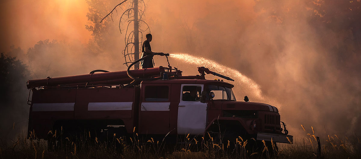 Person on a truck with a hose fighting back wildfire with water