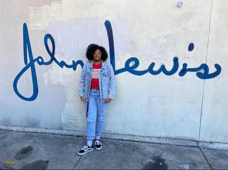 feature author LaTayla Billingslea standing in front of a wall with John Lewis' signature on it
