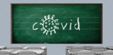 a classroom blackboard with covid spelled out but the o is in the shape of the covid virus