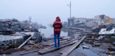 person standing amongst debrief from a tornado or hurricaine