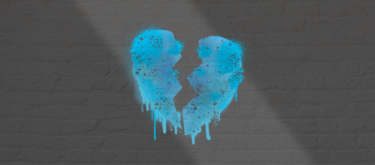a broken heart, in the color blue, spray painted on a grey brick wall