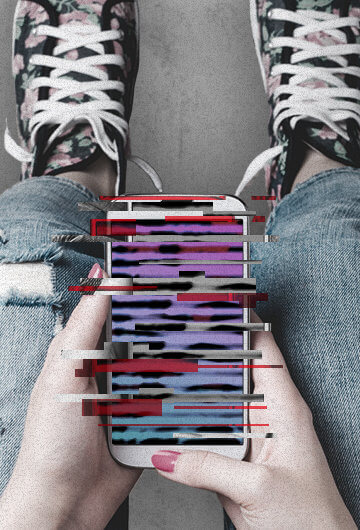 a teen girls legs with her hands resting on her knees looking at a smart phone