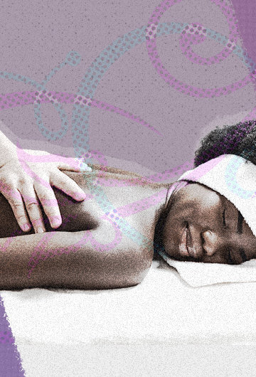 A Black woman, on a massage table, getting a massage. She has a blissful expression on her face.