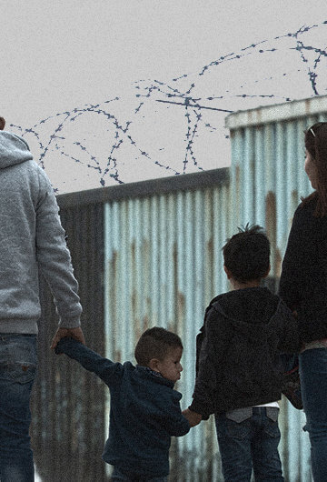 A family stands in front of the USA Mexico Border wall