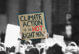 Photo of people protesting, but people's faces are turned the other way. Someone is holding up a sign that says "Climate action is so, so hot right now."